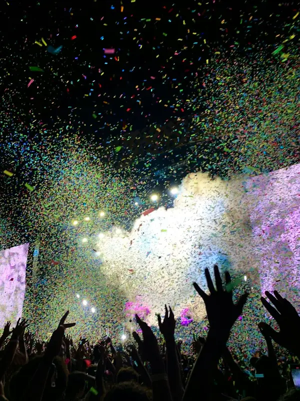 Gold confetti bursting over a concert crowd