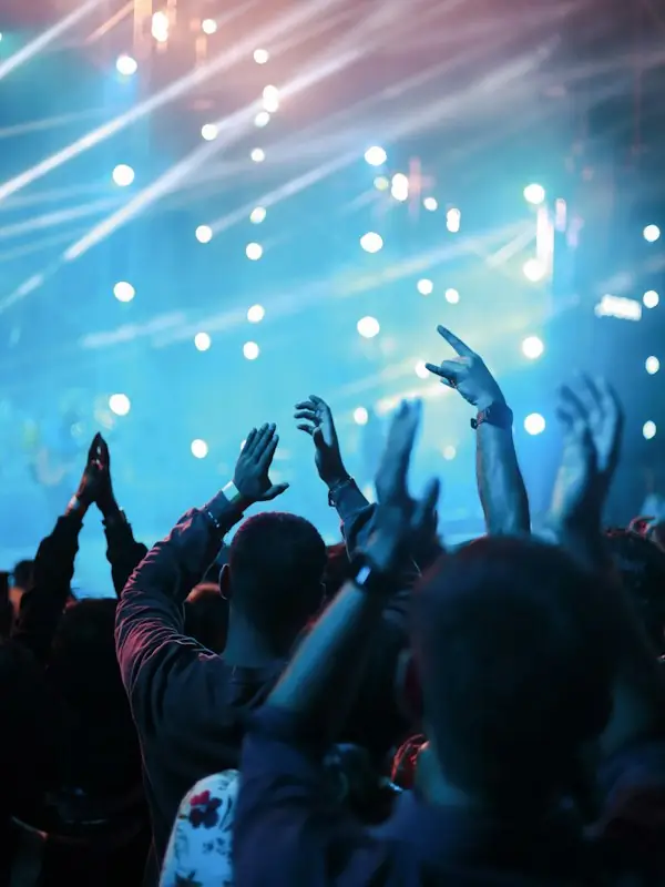 A crowd with hands up under blue stage light