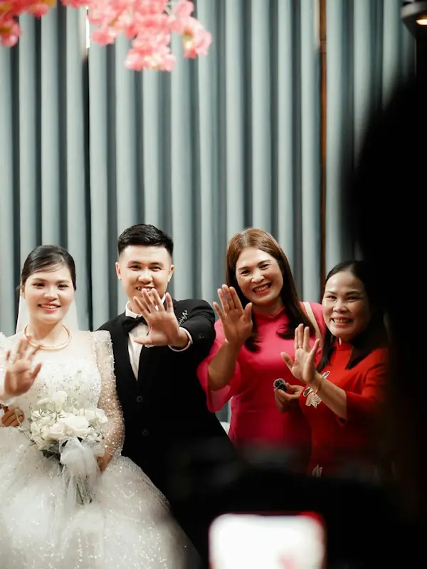 A wedding couple waving with their family